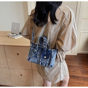 Close-up of vintage washed denim crossbody bag featuring metal buckles and rivet details
