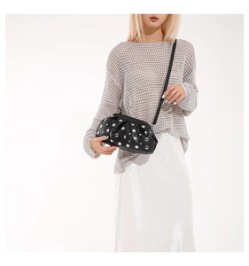 Détail du sac nuage en cuir noir plissé avec rivets argentés porté par un mannequin
