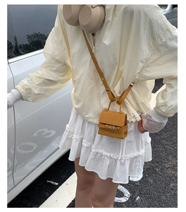 Mini mustard yellow leather flap bag with silver buckle worn as a crossbody accessory