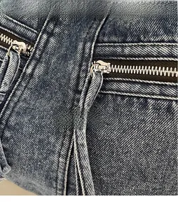 Detailed close-up of blue denim tote bag featuring dual silver metal zippers with long pullers