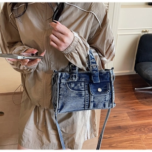 Detail of vintage denim tote bag with functional pockets and silver metal hardware