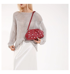 Détail du sac rouge froncé avec rivets argentés et finition cuir à texture de litchi