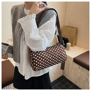 Detail of trendy polka dot cylinder bag with wide leather strap in a cafe setting