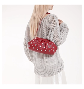 Détail du sac à bandoulière en cuir rouge avec rivets argentés et design plissé élégant