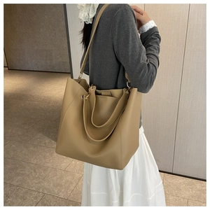 Model wearing a khaki large capacity matte leather tote bag with long shoulder straps