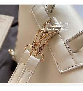 Detailed close-up of premium light gold metal hook hardware on a beige leather handbag