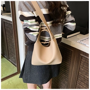 Close-up of beige lychee grain leather bucket bag with wide shoulder strap details
