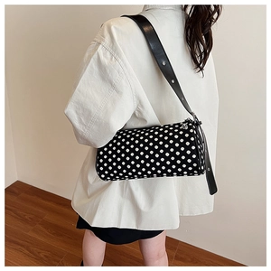 Close-up of the adjustable leather strap and silver zipper on the polka dot cylinder bag
