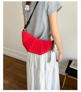 Detailed view of red matte crescent bag featuring side knot strap and bear charm