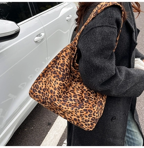 Détail du grand sac cabas à motif léopard porté à l'épaule dans un décor urbain chic