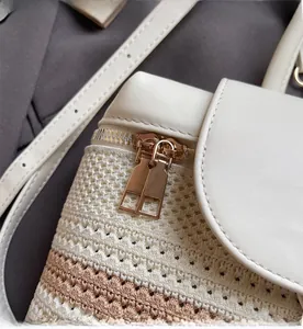 Detail of smooth gold zipper hardware on woven straw and leather patchwork backpack