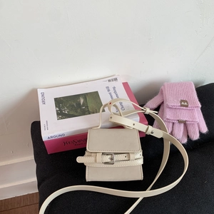 Detail view of mini off-white crossbody bag with flap buckle and adjustable strap