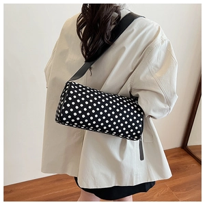 Close-up of retro black polka dot barrel bag with wide leather strap on shoulder