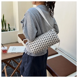 Polka dot pillow bag shown on a shoulder in a casual lifestyle outdoor setting