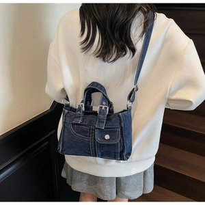 Detail of vintage blue denim handbag with metal buckles and adjustable shoulder strap