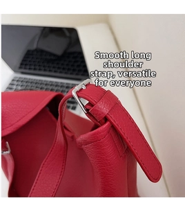 Macro detail of red pebbled leather shoulder strap with adjustable silver metal buckle