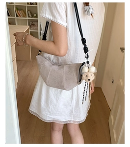 Detail of light gray matte crescent bag with cute plush puppy charm on thin strap