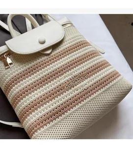 Detail of woven straw backpack with white leather straps and gold metal zipper hardware