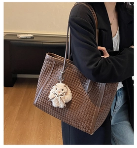 Detail of brown woven tote bag with smooth texture and cute plush rabbit accessory