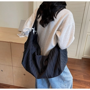 Detail of large black pleated crescent bag showing textured fabric and casual drape