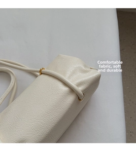 Close-up of the cream leather texture and gold metal ring hardware on the shoulder bag