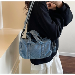 Dettaglio della borsa a secchiello in denim lavato blu con tracolla e mini tasca rotonda