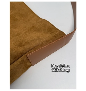 Détail de la texture en daim marron et des coutures précises sur la bandoulière du sac