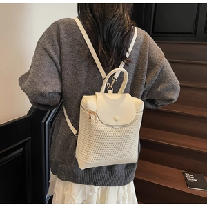 Detail of a beige woven backpack with leather flap and gold hardware on a model