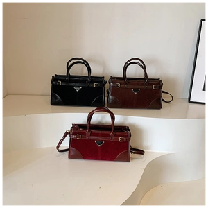 Three suede and leather tote bags in black, brown, and burgundy with metal logos