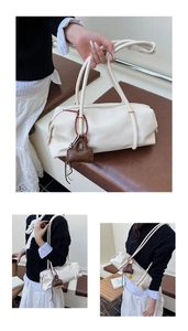 Detail of off-white Boston bag with lychee texture, gold zipper and mini charm