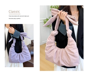 Detail of trendy pleated cloud handbag featuring oversized bow handle in soft lavender