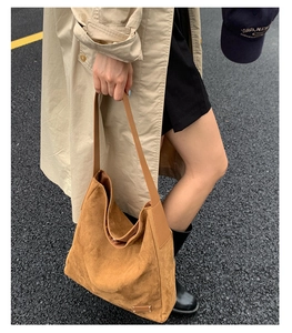 Gros plan sur le daim marron du sac seau avec détail métallique et bandoulière en cuir