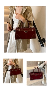 Close-up of wine red patent leather handbag featuring a signature black triangle metal logo