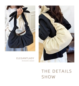 Detail of oversized bow shoulder strap and pleated fabric on cloud-style tote bag