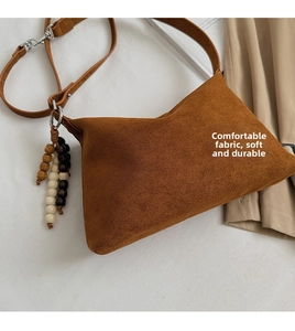 Detailed close-up of a vintage brown suede dumpling bag featuring wooden bead charms