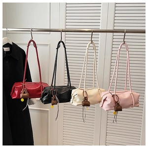 Boston barrel bags in red, black, white, and pink leather hanging on a display rack