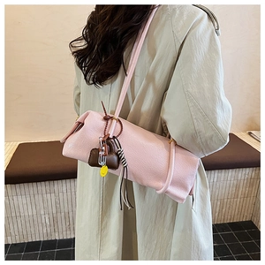 Detailed side view of pink cylinder tote with heart charms and striped tassel on model