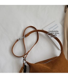 Close-up detail of the adjustable strap and bead charms on a brown suede hobo bag