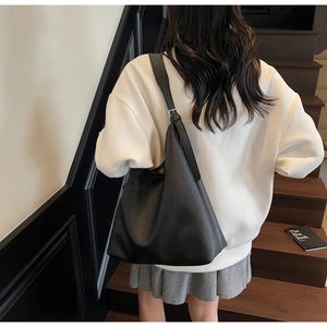 Rear view of a model wearing a large black leather tote bag on wooden stairs