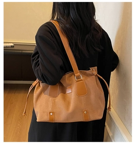 Rear view of a person wearing a large brown suede tote bag with drawstring details