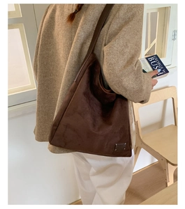 Gros plan d'un sac cabas en daim marron foncé avec une étiquette décorative minimaliste