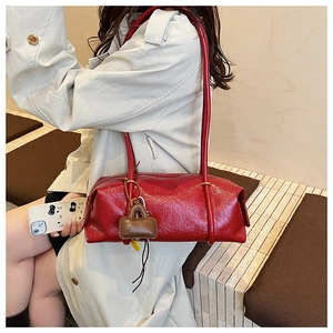 Detail of red glossy leather Boston bag with long straps and lock pendant decoration