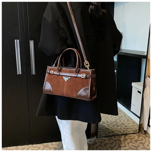 Detailed side view of a brown vintage satchel featuring matte leather and metal plate