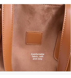 Detailed close-up of brown suede tote bag featuring smooth leather accents and white stitching