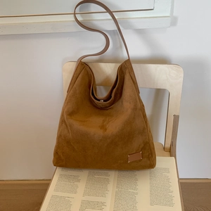 Close-up of brown suede hobo bag on wooden chair with vintage lifestyle vibes