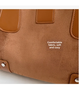 Detailed close-up of brown suede fabric with leather trim and silver metal rivets