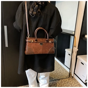Close-up of brown matte suede handbag with black triangle detail and golden hardware