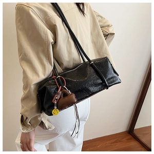 Close-up of black pleated Boston shoulder bag featuring a cute mini charm and smile tag