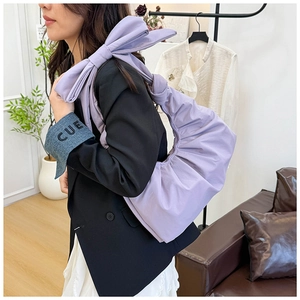 Detail showing lavender ruched shoulder bag with oversized bow strap and soft pleated fabric