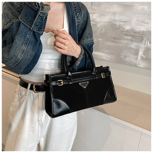 Detailed view of black matte leather handbag featuring iconic golden triangular hardware